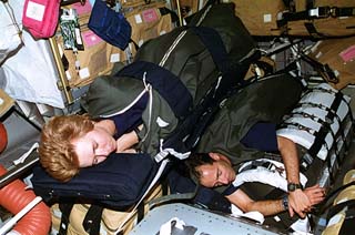 STS-84 Mission Specialists Elena Kondakova and Jean-Francois Clervoy demonstrate the sleep restraints arrangement in the Spacehab module.